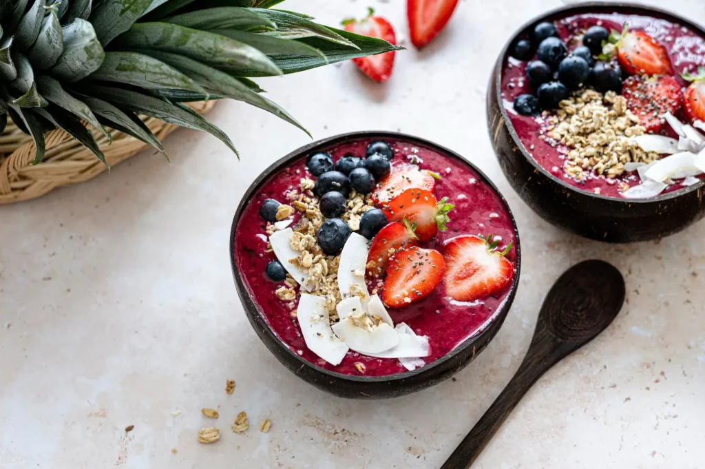 A vibrant Organic Berry Smoothie Bowl topped with fresh blueberries, raspberries, granola, coconut flakes, and pumpkin seeds, served in a white bowl on a rustic wooden table—perfect for a healthy, antioxidant-rich breakfast idea.