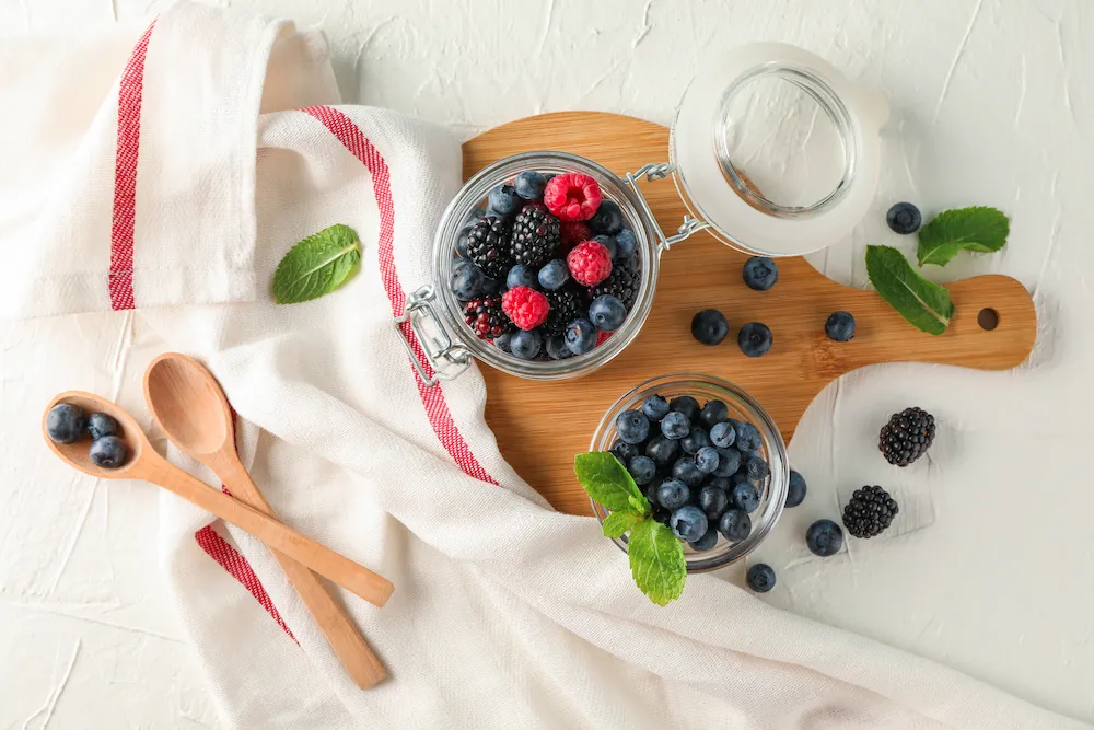 Fresh organic strawberries, blueberries, and raspberries in a rustic wooden basket, rich in skin-protecting antioxidants.