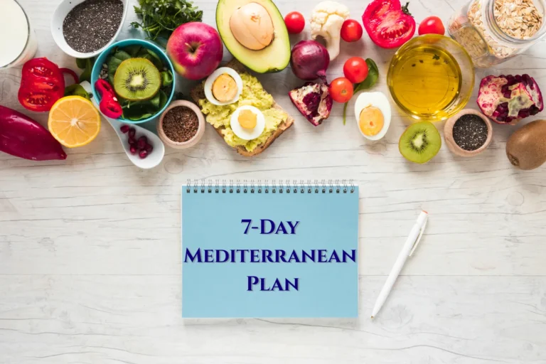 A blue meal planning notepad and pen sit among Mediterranean diet staples like oats, fresh pomegranate, olive oil, and avocado toast.