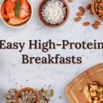Overhead flat-lay of healthy whole foods like smoked salmon, eggs, and avocado surrounding the title text Easy High-Protein Breakfasts.