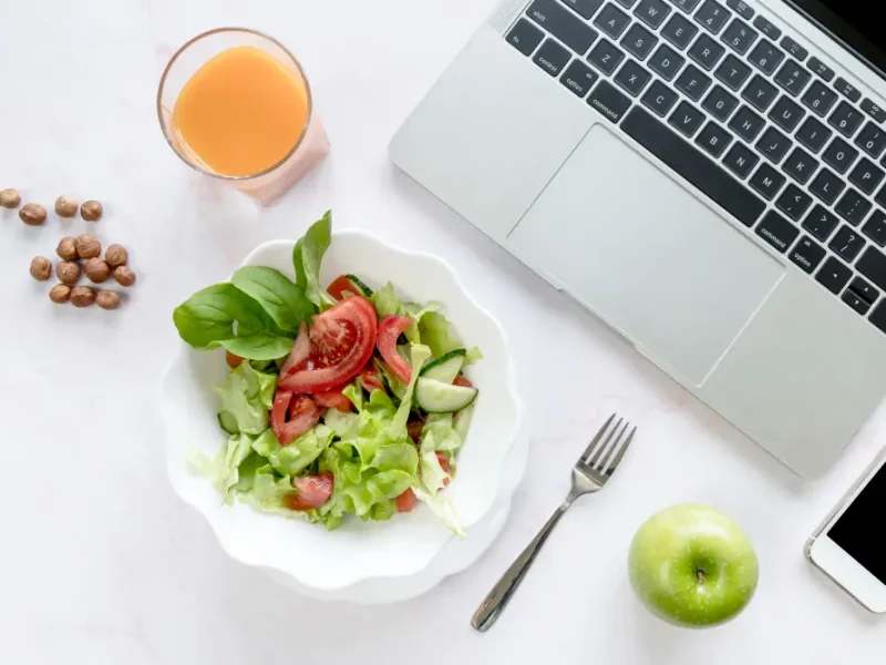 Healthy editorial team workspace with laptop, fresh salad and juice on desk at My Pure Organics